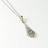 Collier Art Deco avec un diamant central et un motif délicat, fabriqué en or jaune et blanc 18K. Comprend 3 diamants taille rose pour une élégance intemporelle.