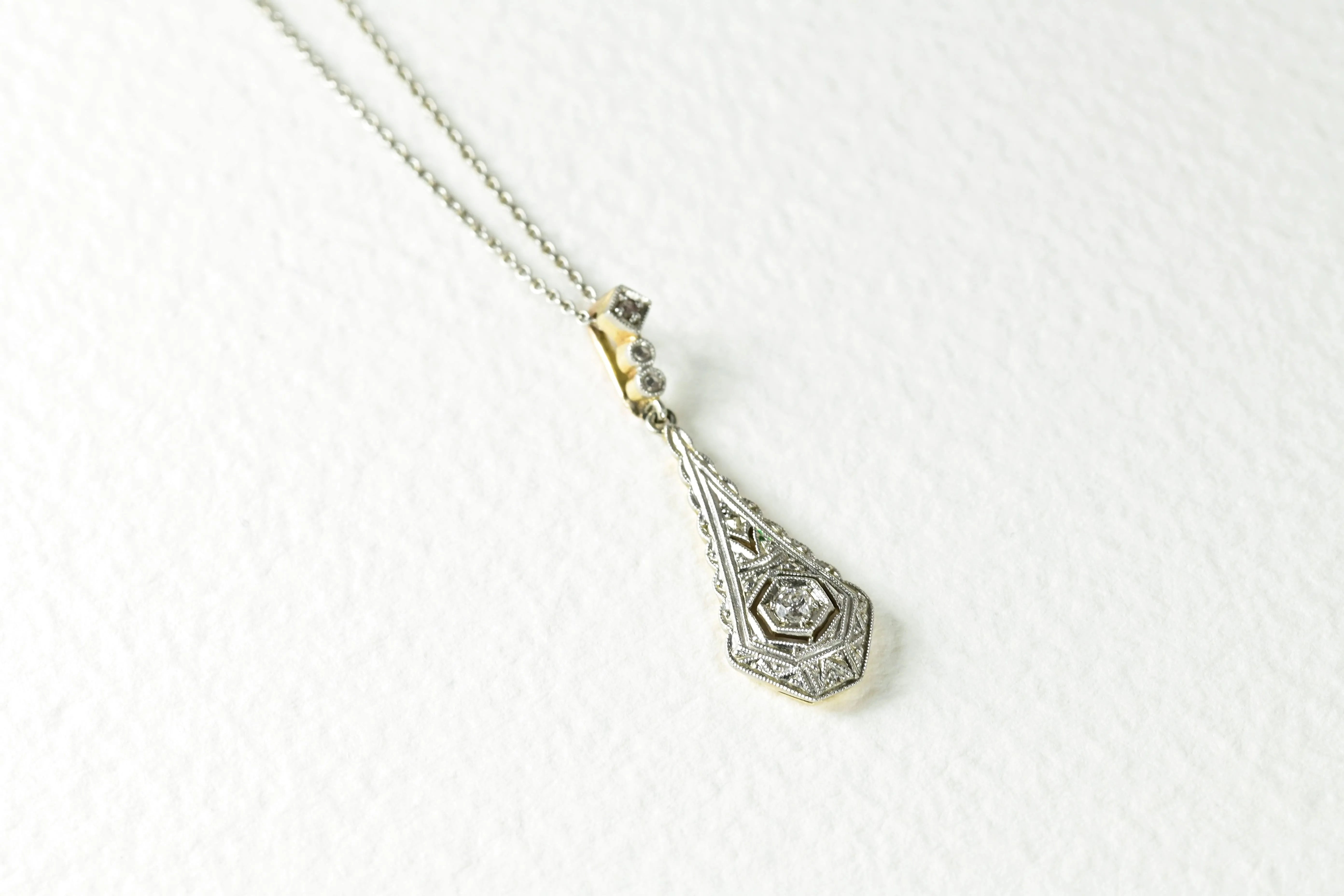 Collier Art Deco avec un diamant central et un motif délicat, fabriqué en or jaune et blanc 18K. Comprend 3 diamants taille rose pour une élégance intemporelle.
