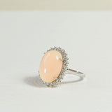 Bague en corail peau d'ange avec un halo de diamants.