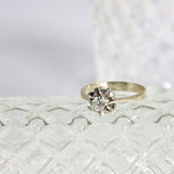 Bague solitaire étoile avec un diamant central rond en or blanc 18K. Design étoile élégant.