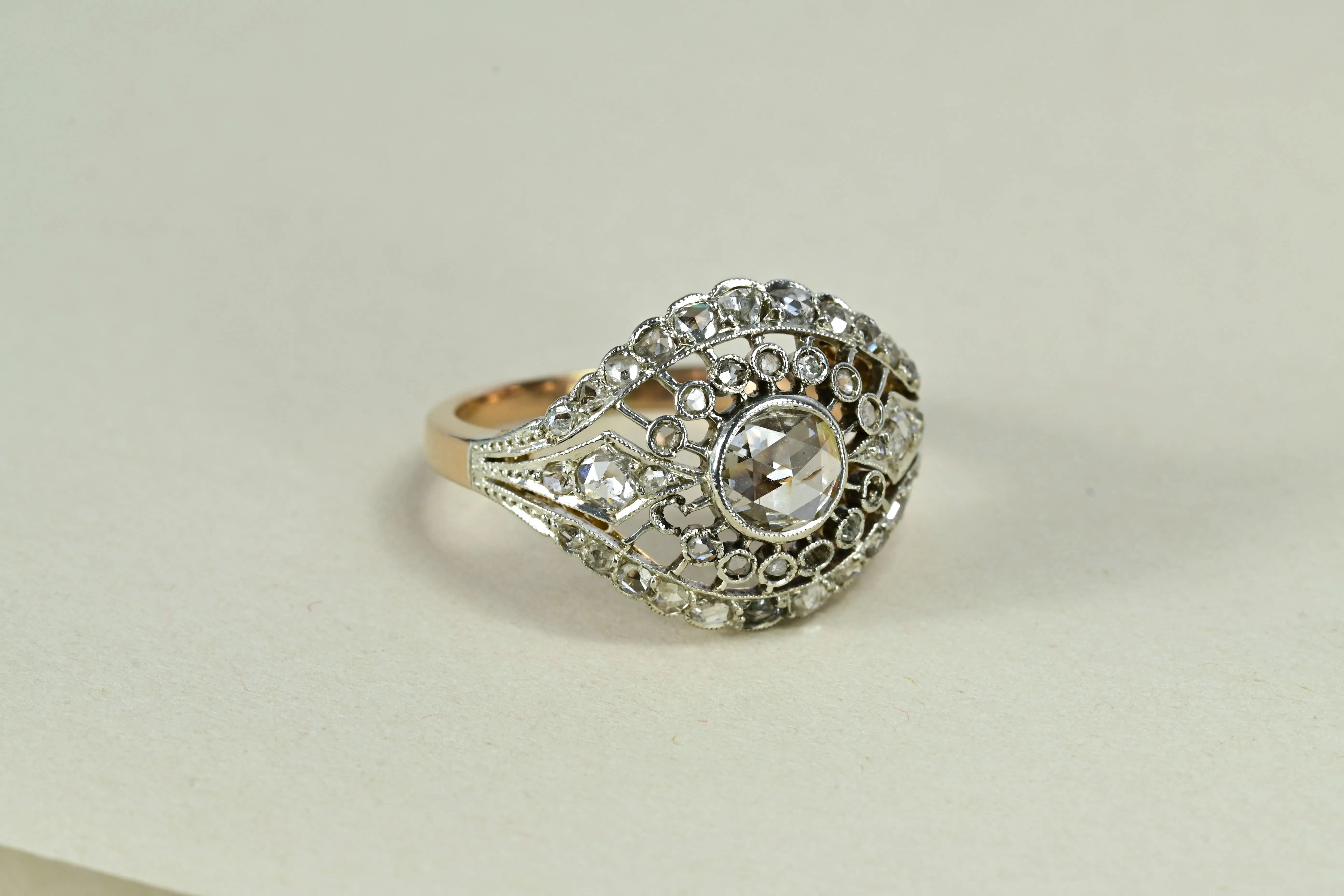 Anillo de diamantes modernista en oro amarillo y blanco de 14k con un diamante central cortado en rosa holandés rodeado de 42 diamantes más pequeños.