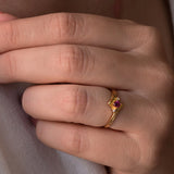 Vintage ruby and diamond ring in 14K yellow gold, featuring a central round cut ruby and two diamonds.