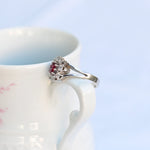 Vintage Blütenring mit zentralem Rubin und acht natürlichen Diamanten in 14K Weißgold.