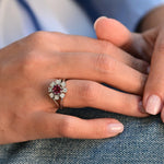Vintage flower-shaped ring with central ruby and eight natural diamonds in 14K white gold.