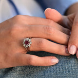 Vintage flower-shaped ring with central ruby and eight natural diamonds in 14K white gold.