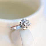 Bague de fiançailles avec diamant rond en or blanc 18K et 14 diamants entourants.
