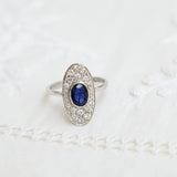Anillo vintage con zafiro ovalado y diamantes, en oro blanco de 18K.