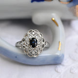 Bague vintage en platine avec saphir ovale et diamants ronds.