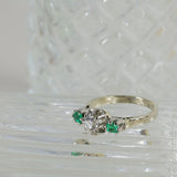 Anillo de compromiso de diamante con 2 esmeraldas naturales.