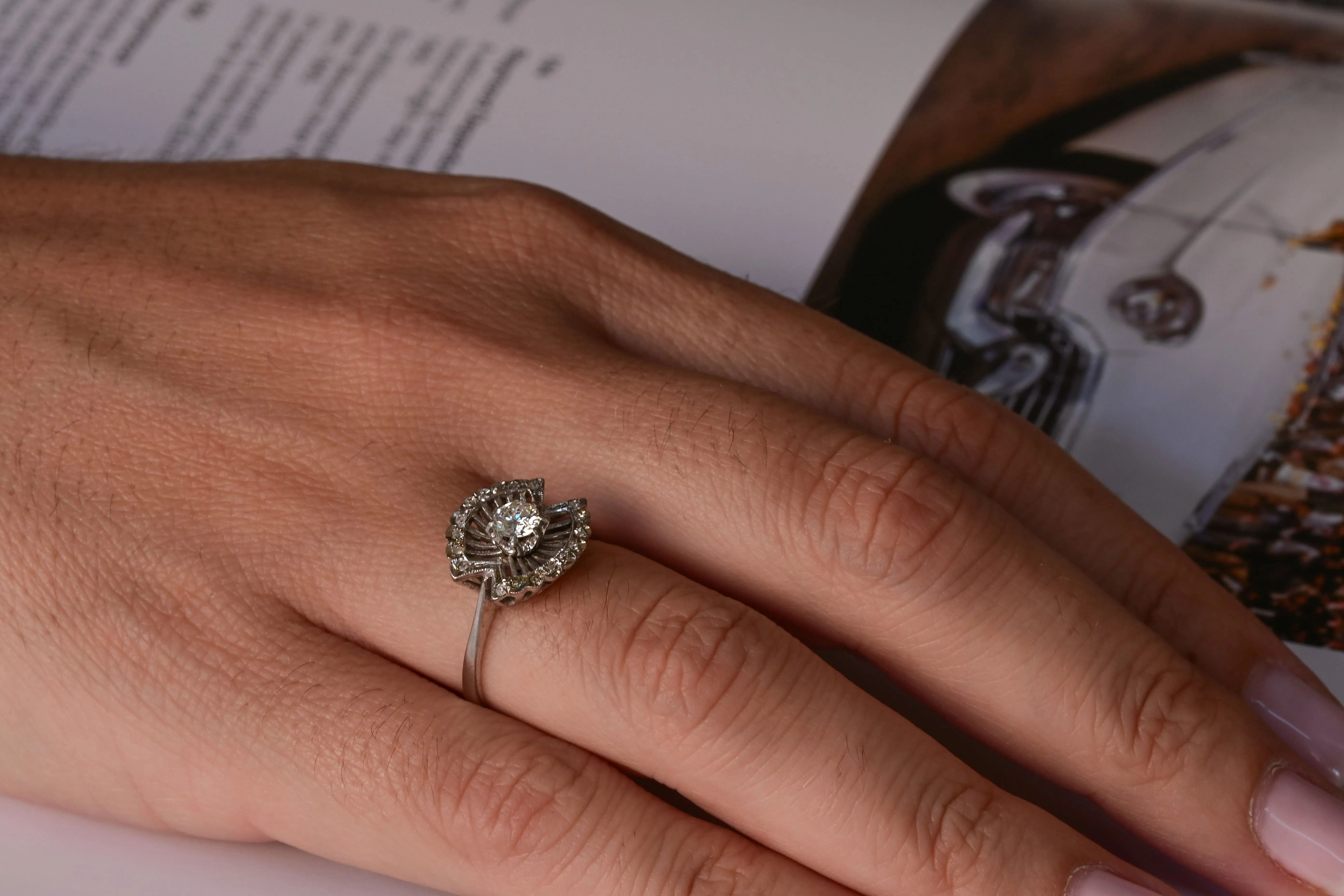 Mid-20th century diamond engagement ring with a central diamond and 18 pave-set diamonds in 18k white gold.