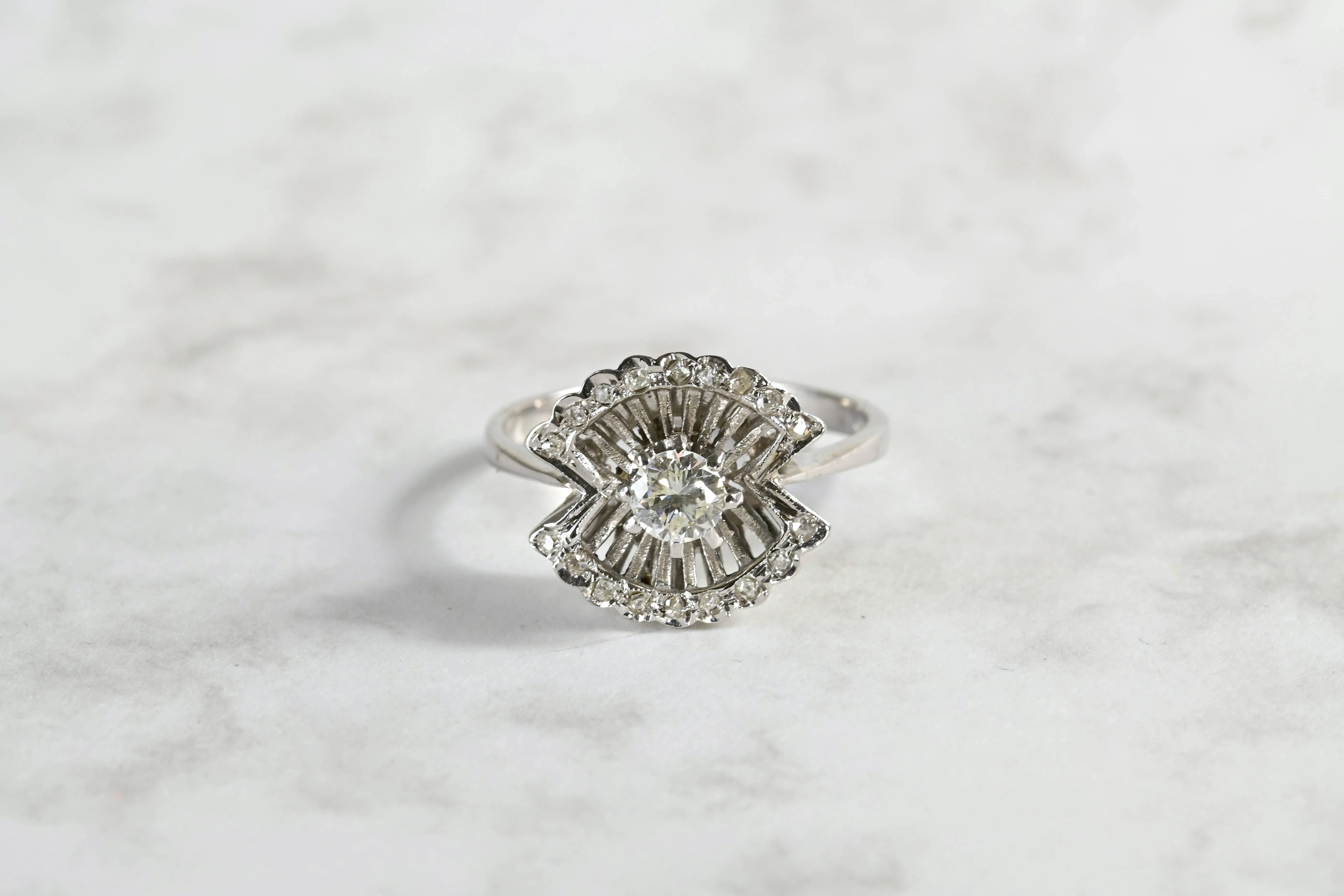 Bague de fiançailles du milieu du 20e siècle avec un diamant central et 18 diamants en pavé, en or blanc 18k.