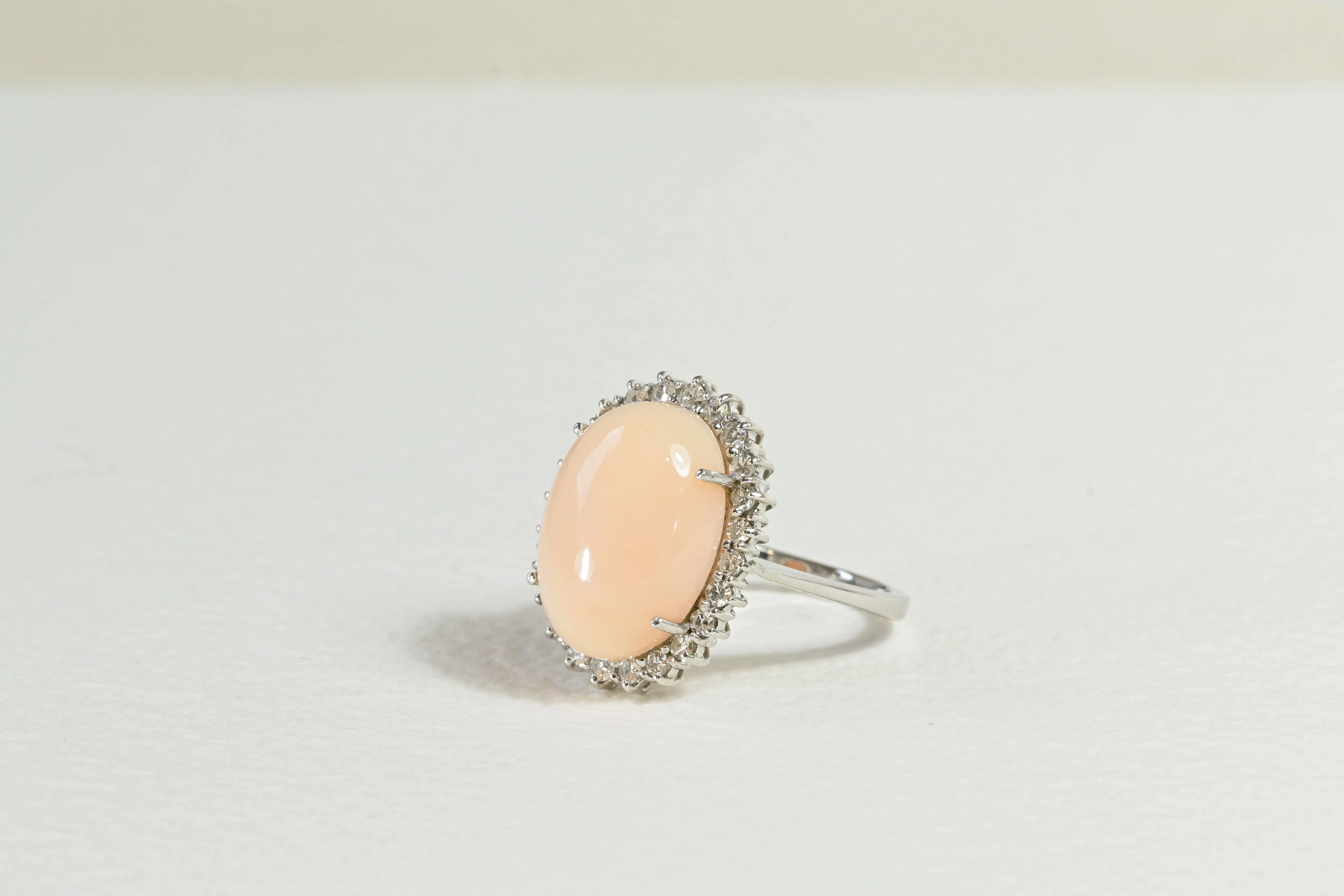 Bague en corail peau d'ange avec un halo de diamants.