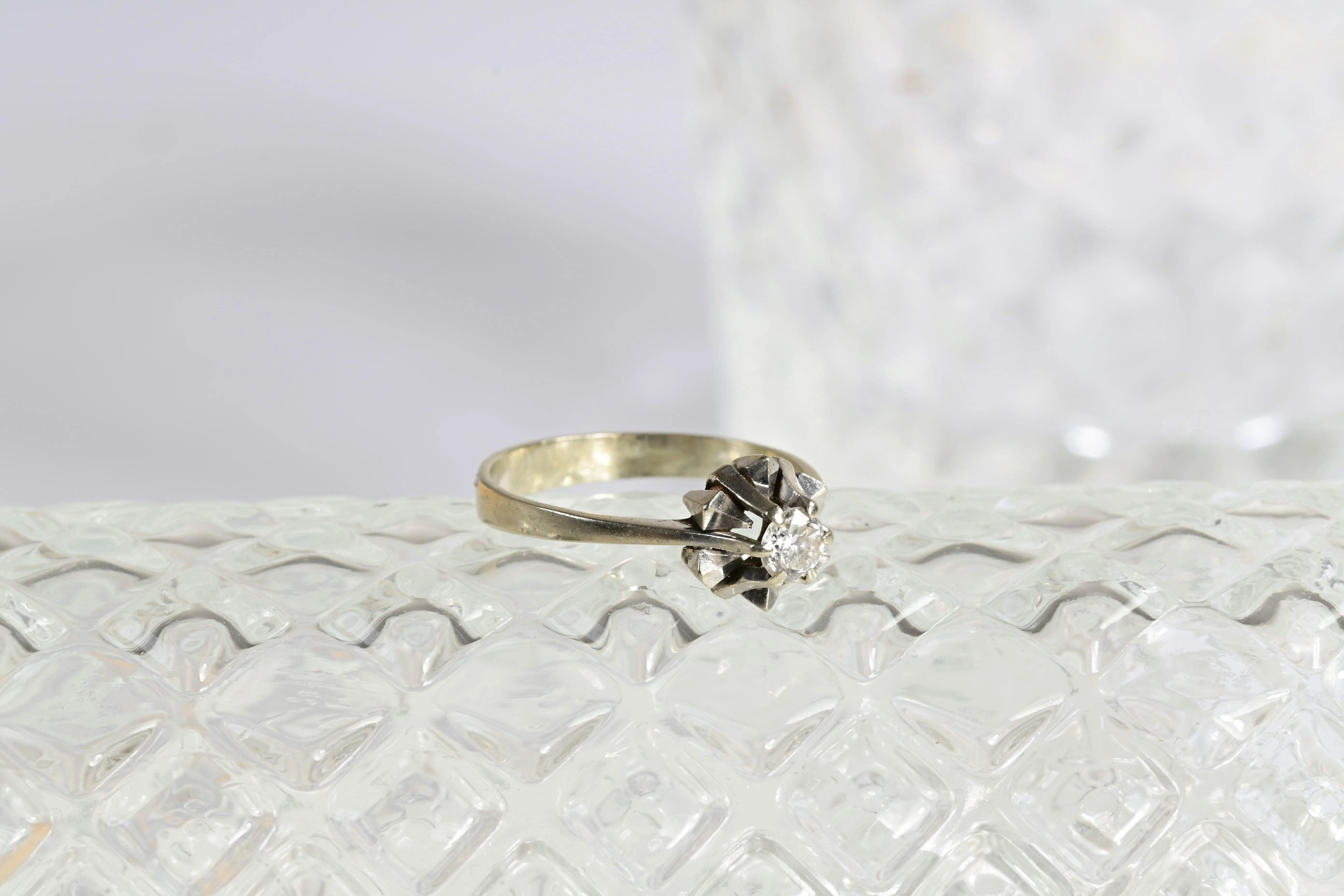 Anillo solitario con forma de estrella, con un diamante central redondo en oro blanco de 18K. Diseño elegante en forma de estrella.