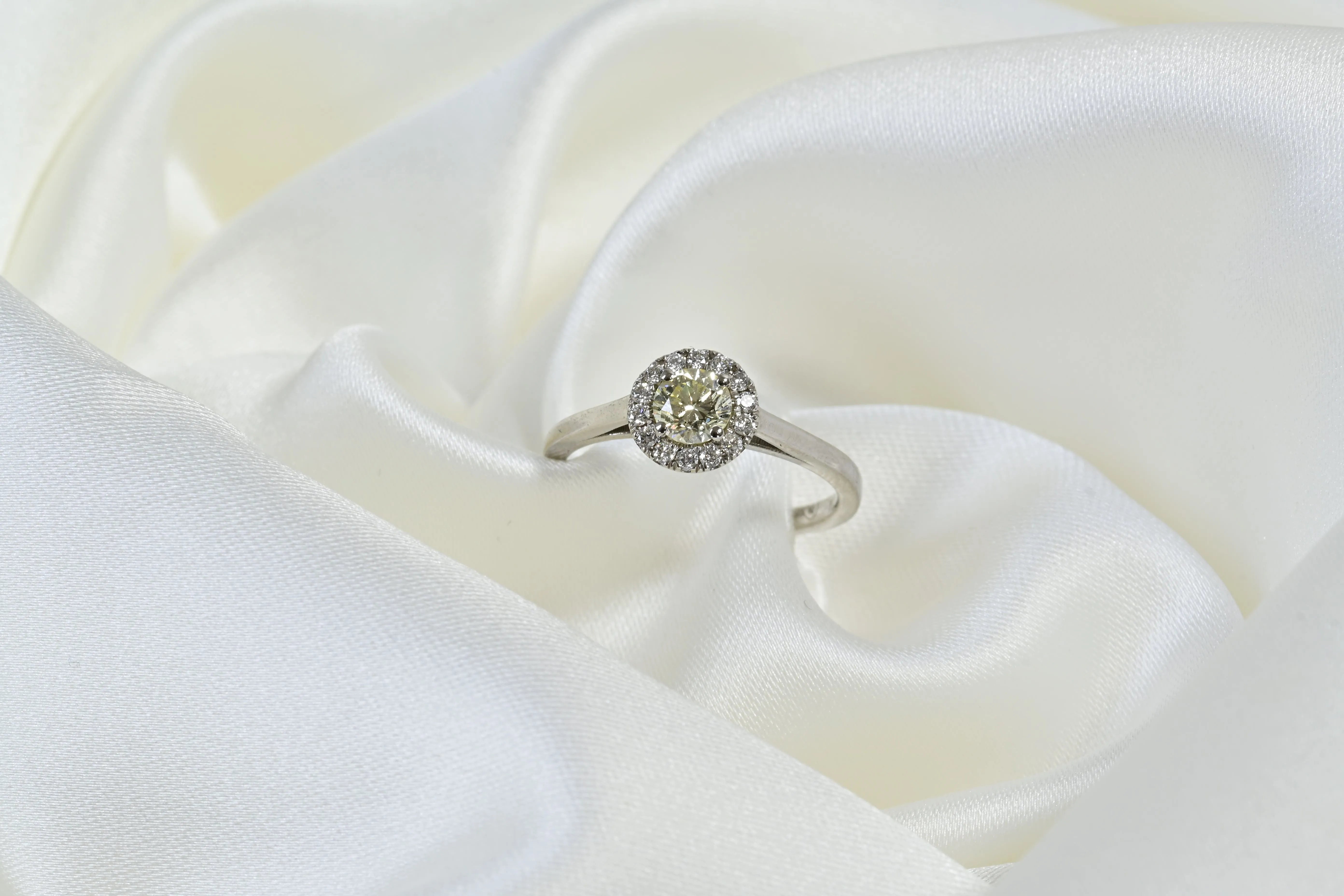 Anillo de compromiso con diamante amarillo y halo de diamantes blancos, en oro blanco de 14k.