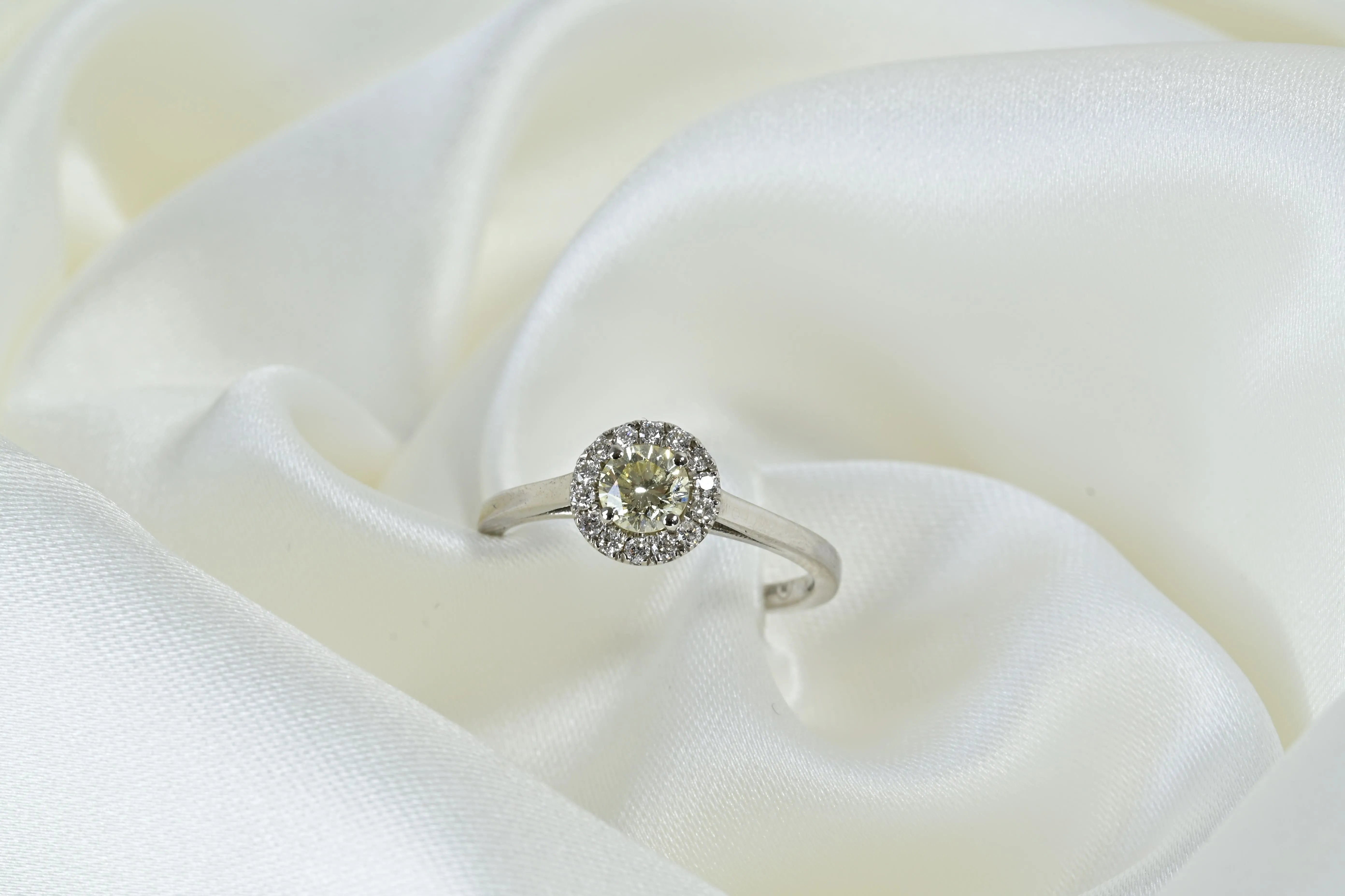 Yellow diamond engagement ring with a halo of white diamonds, set in 14k white gold.