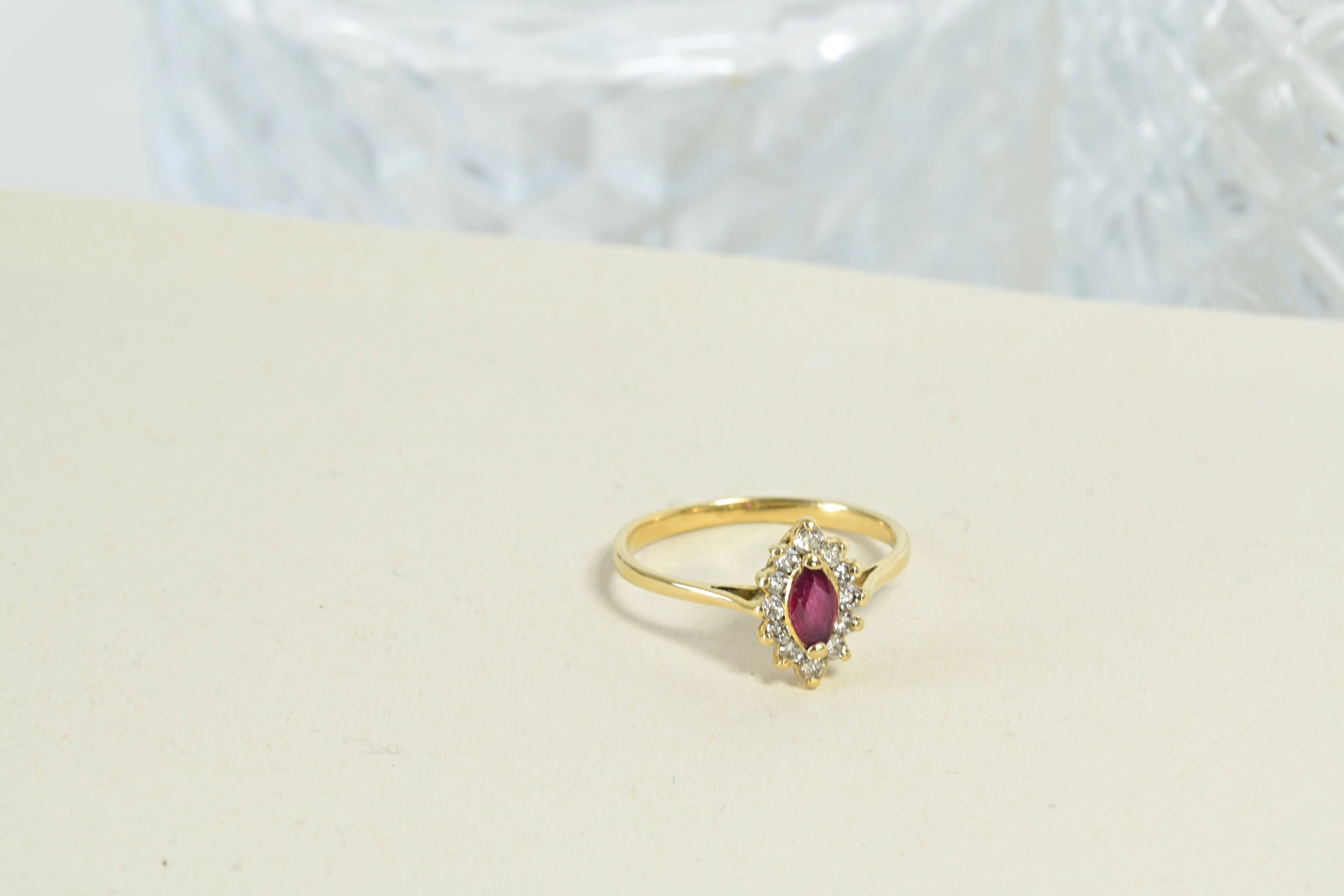 Antique rosette ring with a central shuttle-cut ruby and 12 diamonds in 18k yellow gold, showcasing intricate floral design.