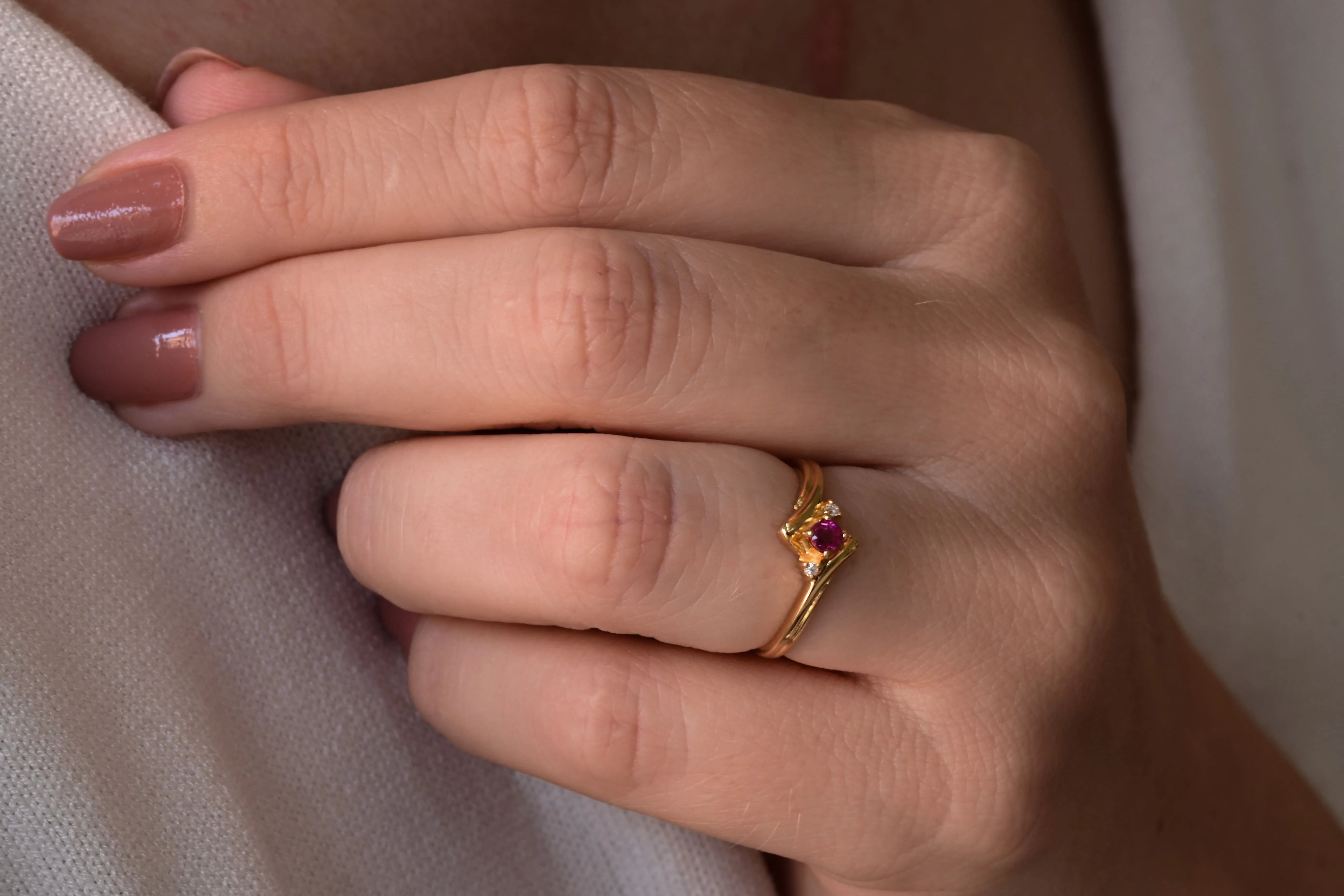 Vintage ruby and diamond ring in 14K yellow gold, featuring a central round cut ruby and two diamonds.