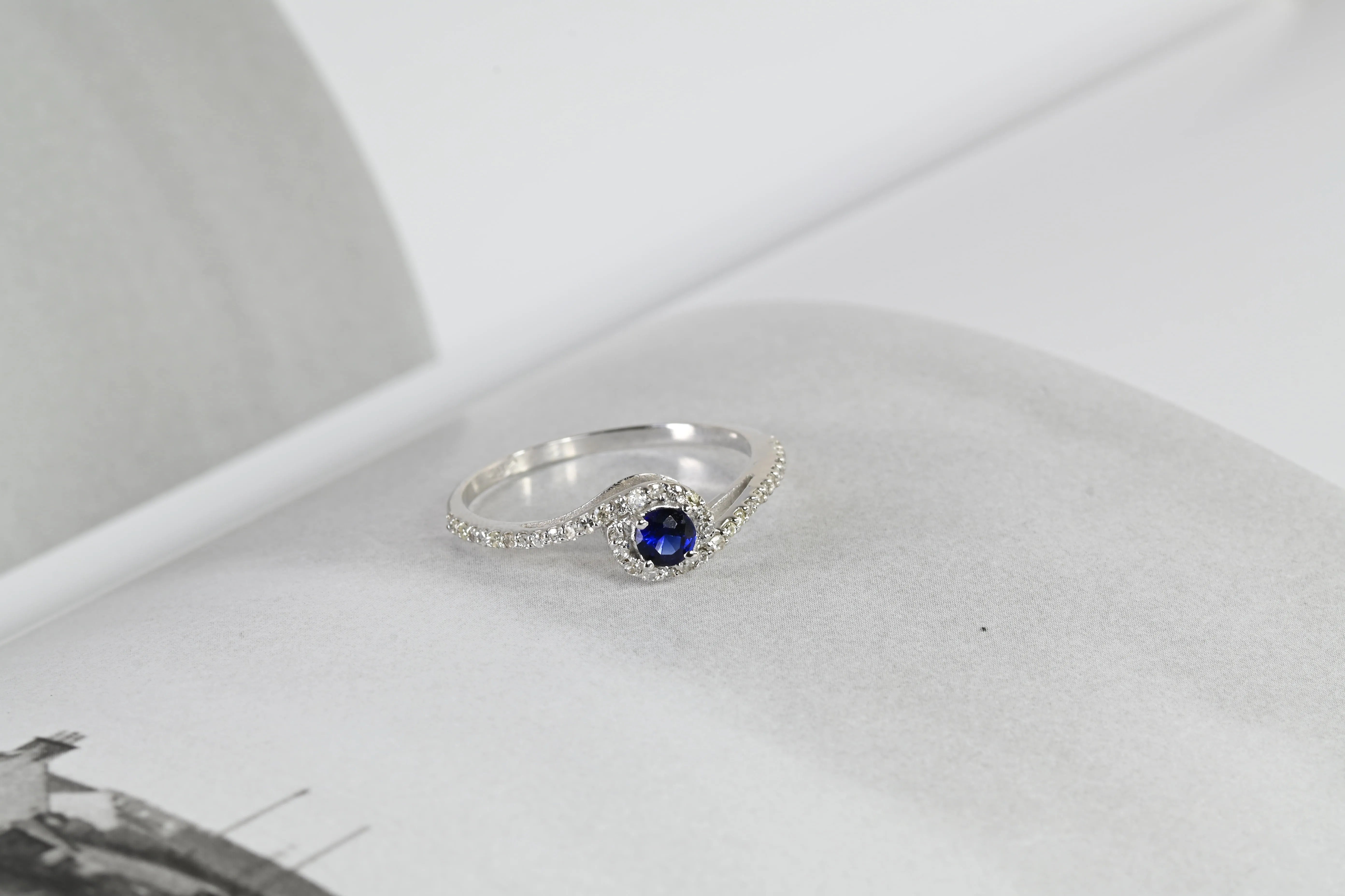 Bague vintage avec un saphir bleu profond central et un halo de 44 diamants, en or blanc 18K.