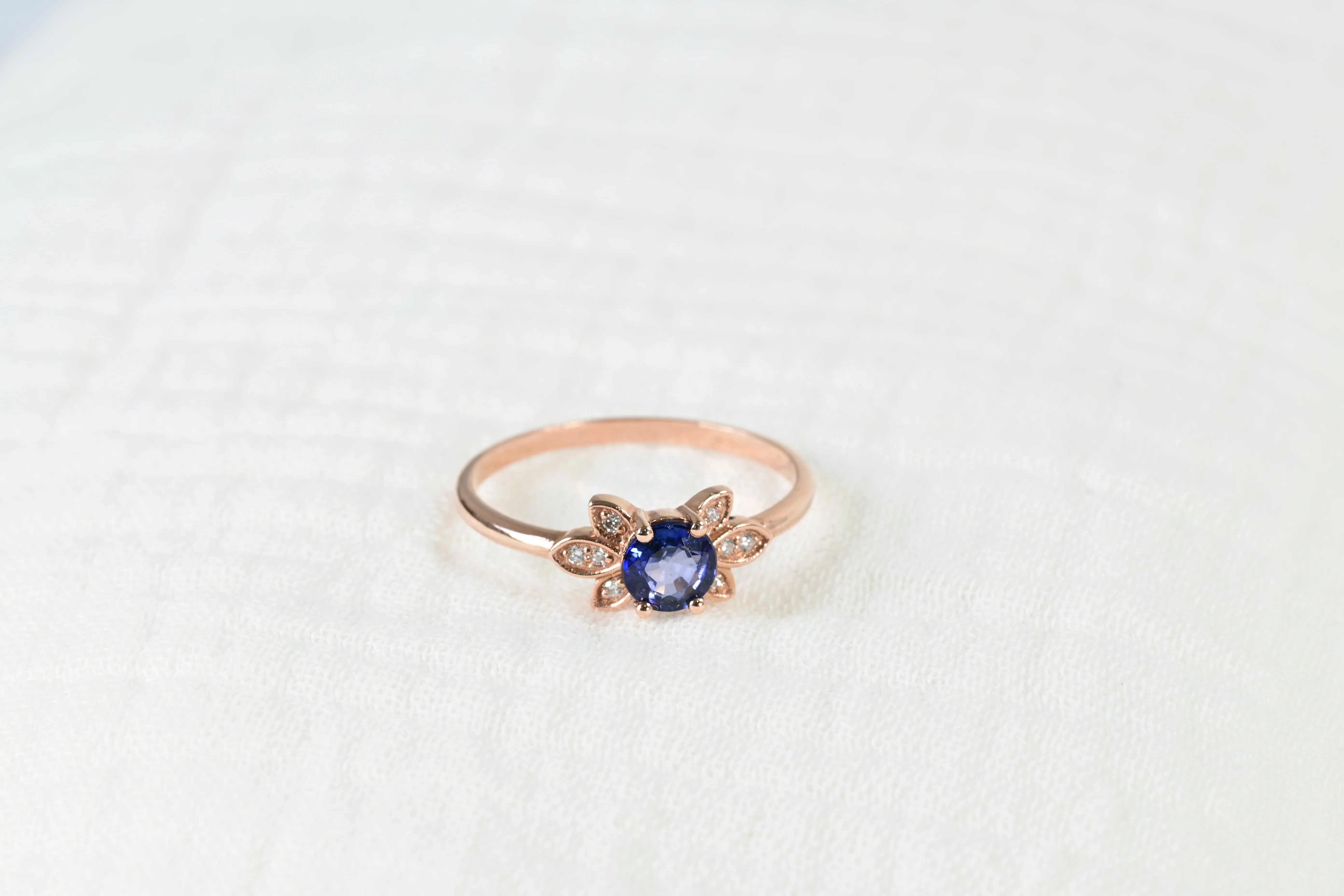 Vintage-Ring mit zentralem blauen Saphir und 8 Diamanten in 14K Roségold.