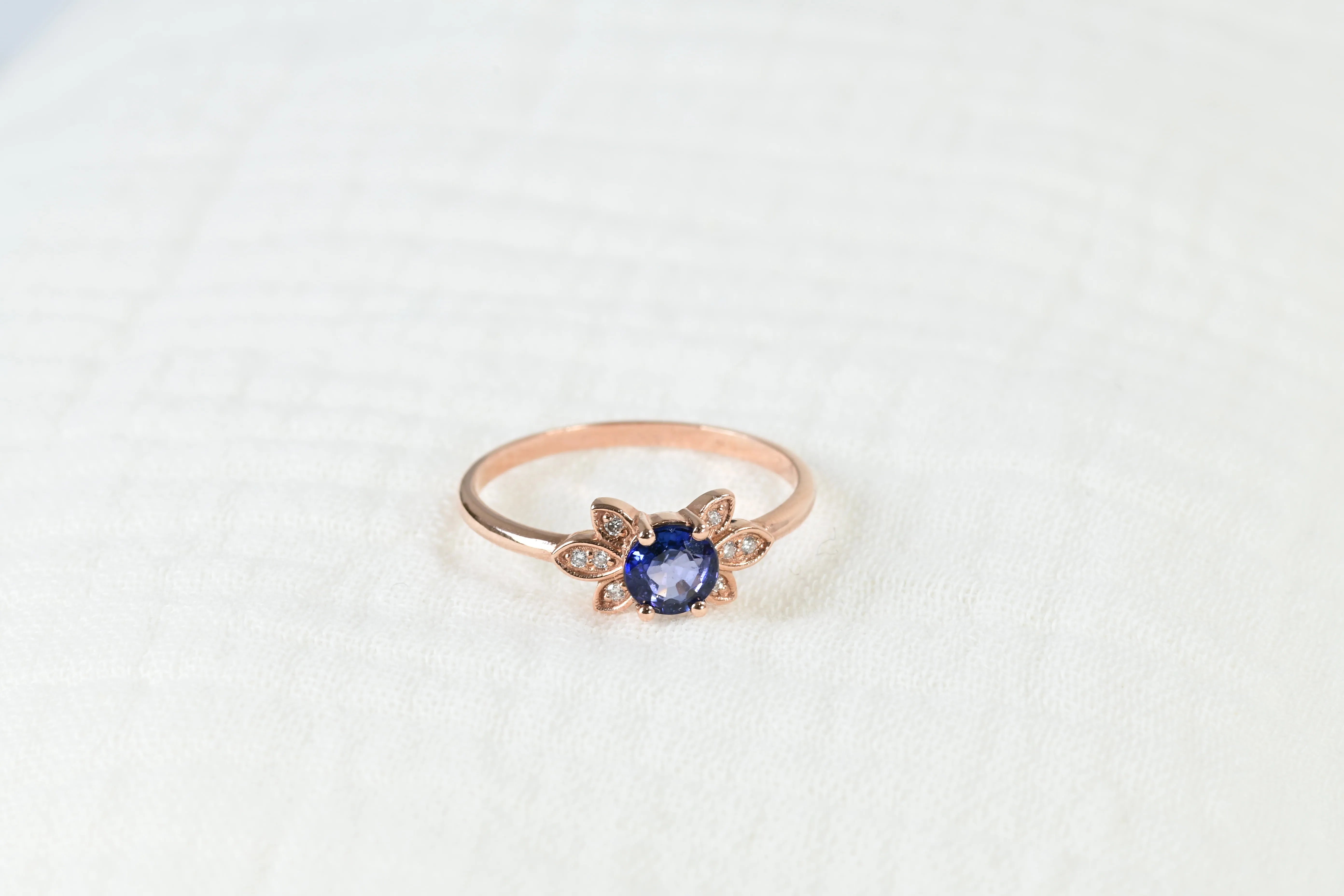 Vintage ring featuring a central blue sapphire and 8 diamonds in 14K rose gold setting.