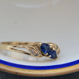 Elegant vintage ring featuring two pear-shaped sapphires in rich blue tones, accented by four shimmering single-cut diamonds.