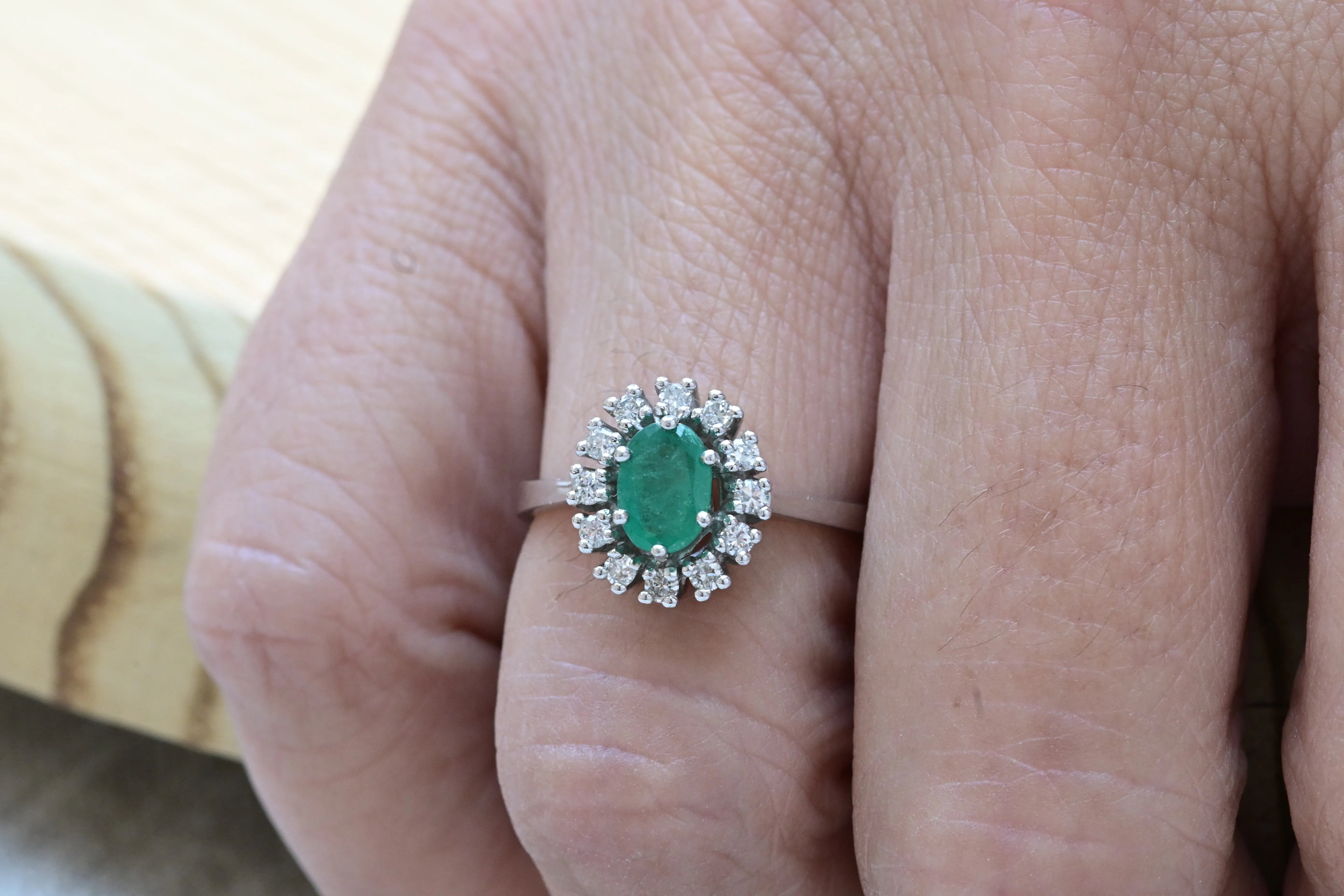 Anillo de cóctel vintage con un esmeralda central de corte ovalado y 12 diamantes.