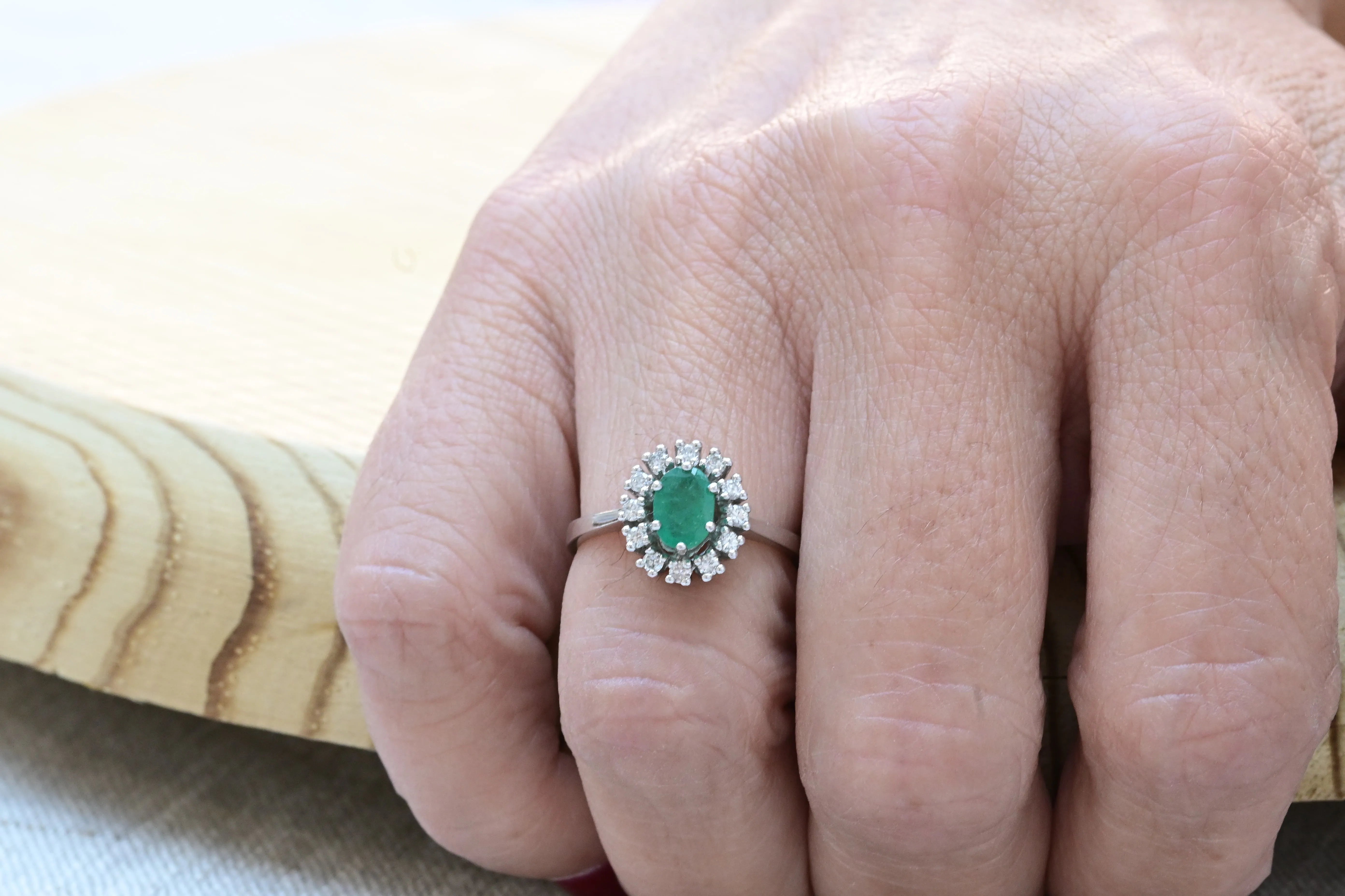 Vintage cocktail ring with a central oval cut emerald and 12 diamonds.