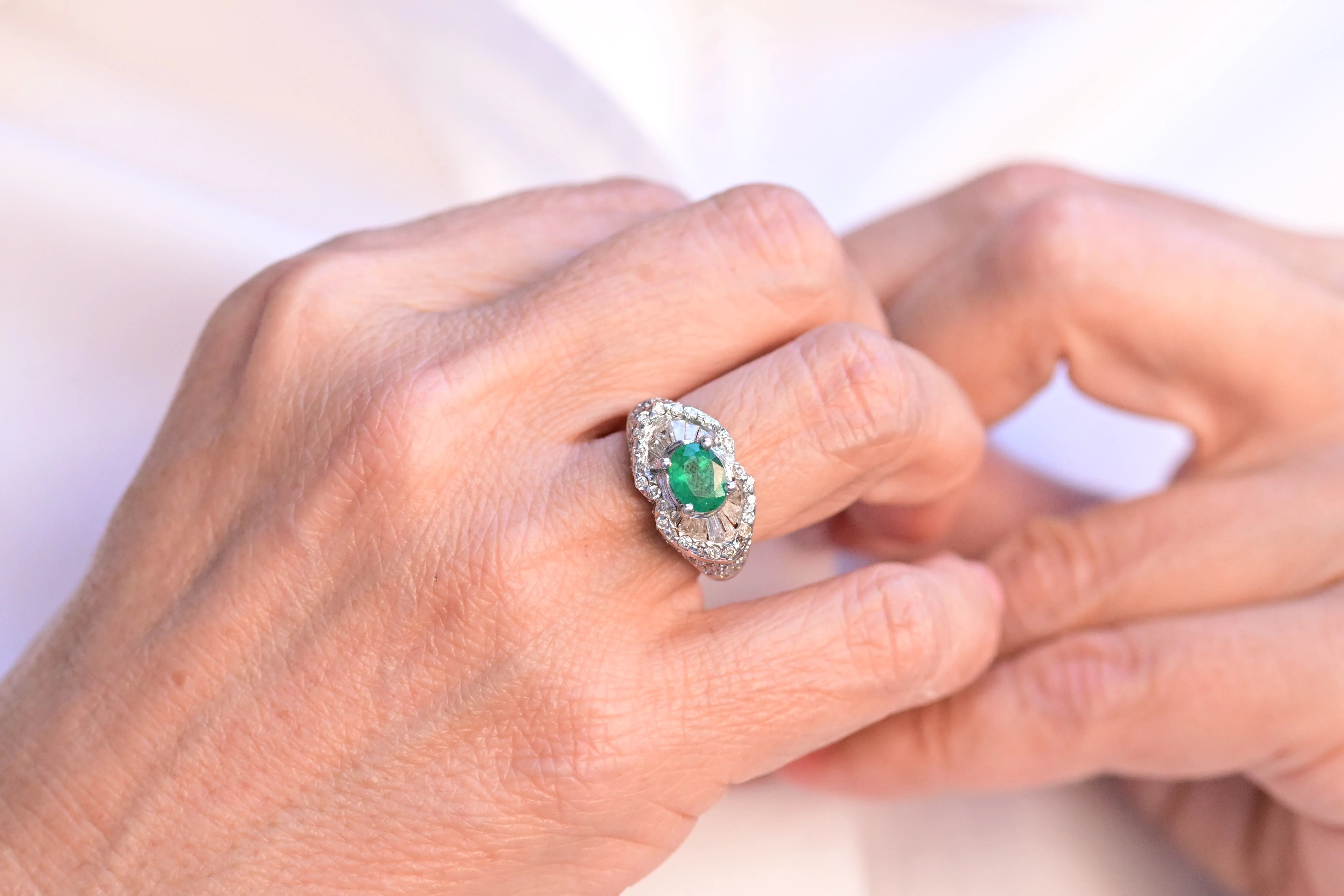 Vintage ring featuring a central teal oval cut emerald and 87 diamonds set in 18K white gold.