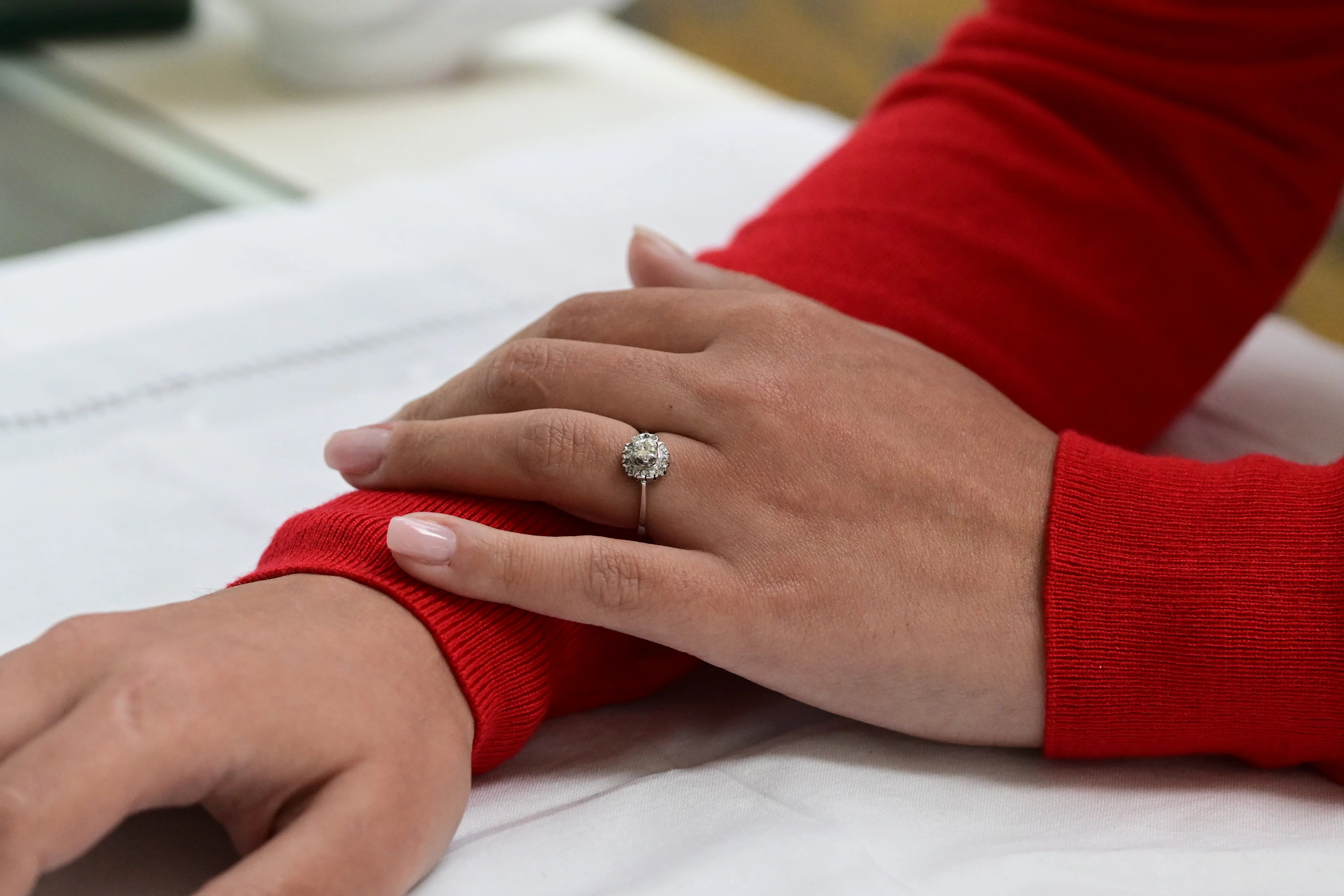 Anillo de compromiso con diamante redondo en oro blanco de 18K y 14 diamantes alrededor.