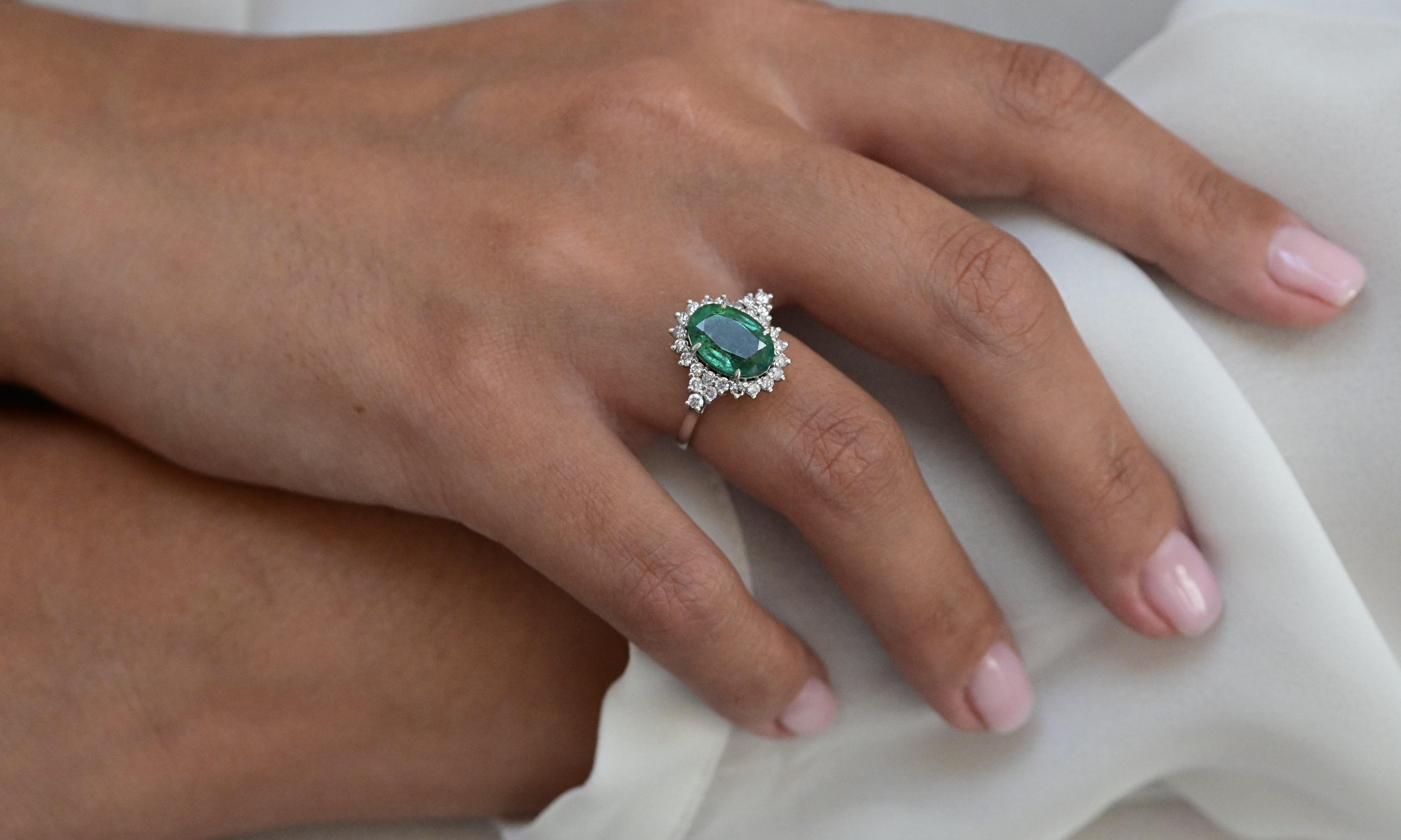 Vintage ring featuring a bluish green emerald and 26 round brilliant cut diamonds in white gold.