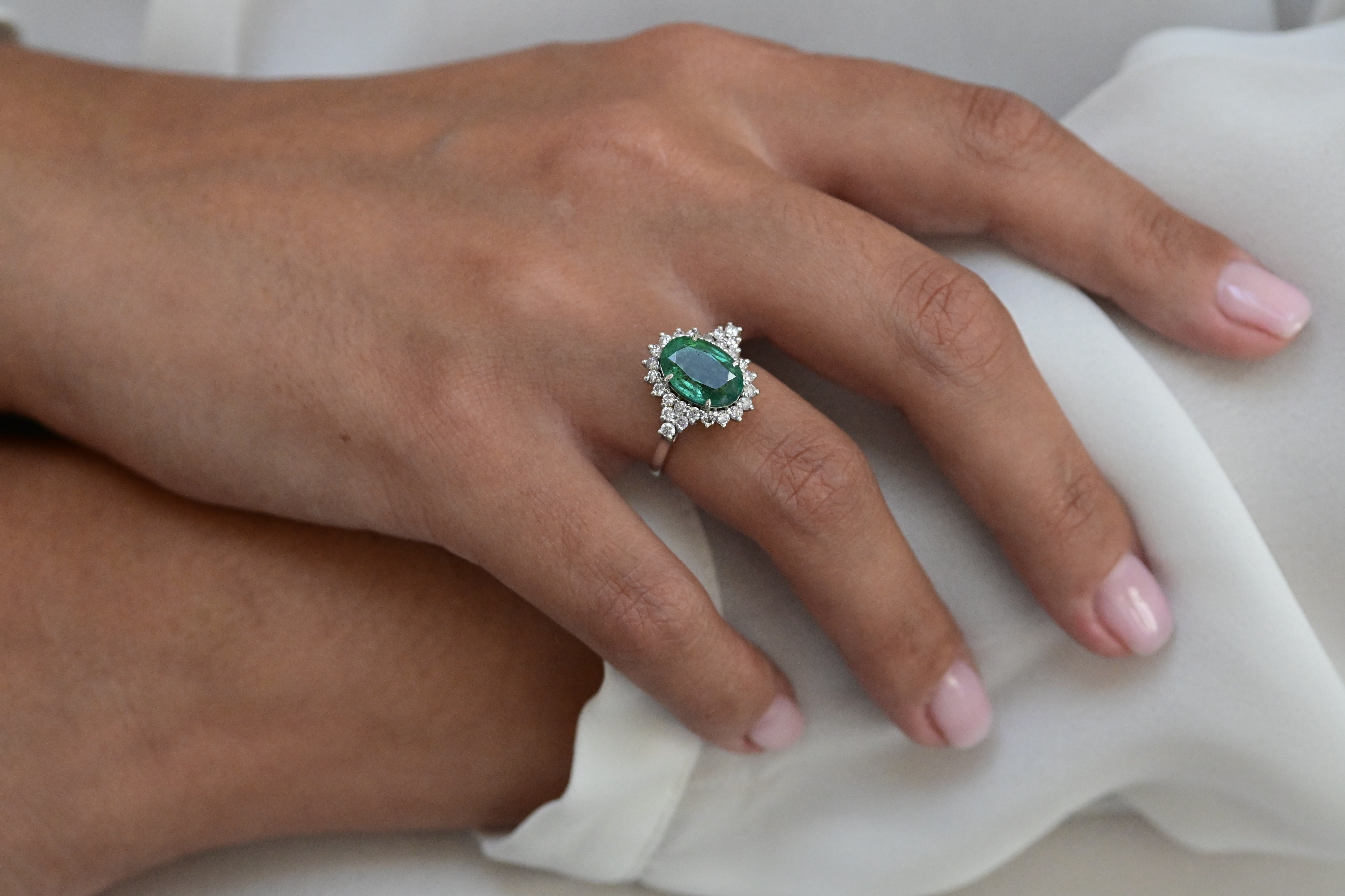 Vintage ring featuring a bluish green emerald and 26 round brilliant cut diamonds in white gold.