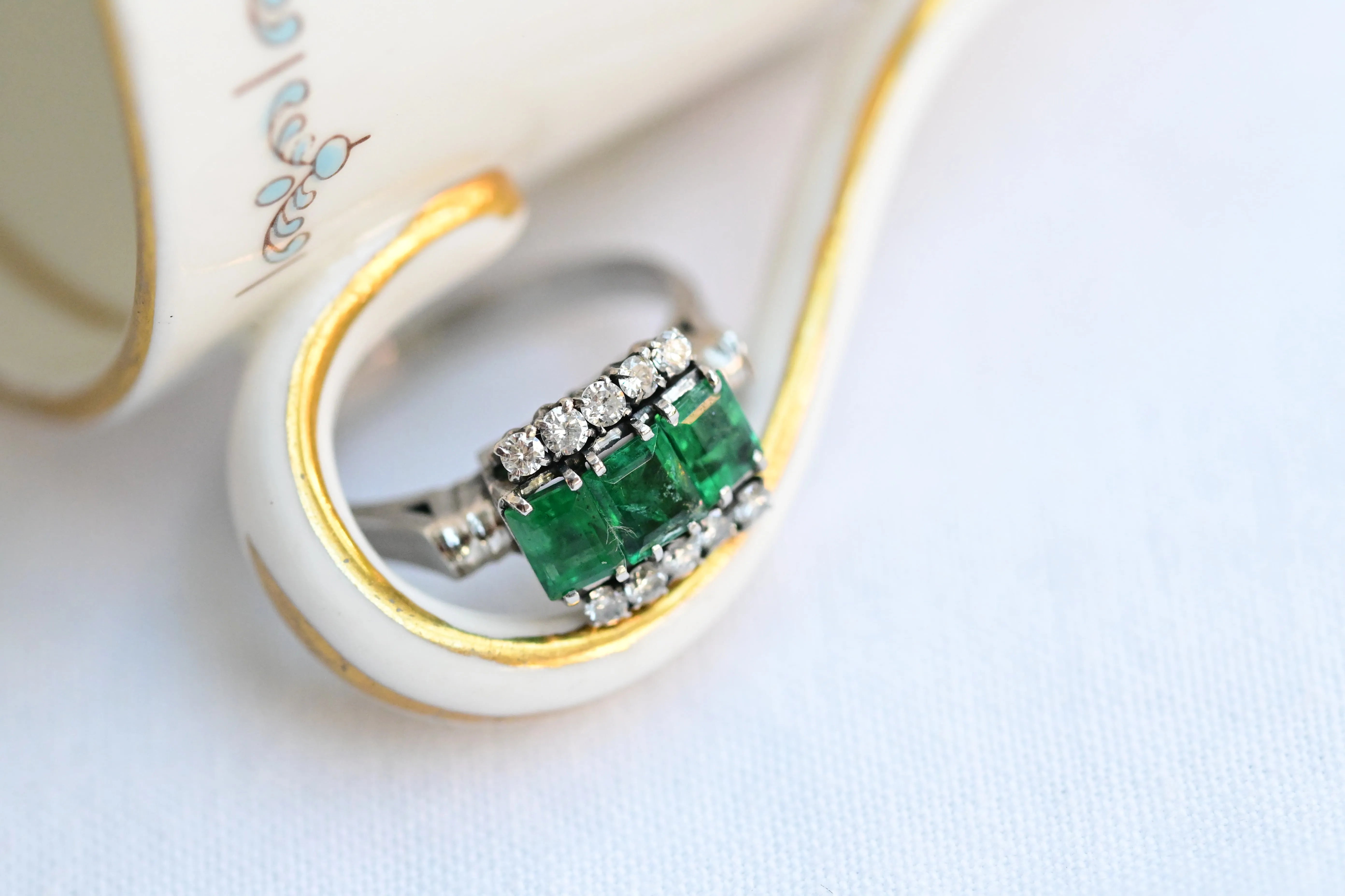 Vintage ring with 3 central emeralds and 10 round cut diamonds, set in 18K white gold.