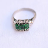 18K white gold vintage ring featuring 3 emeralds surrounded by 10 round cut diamonds.