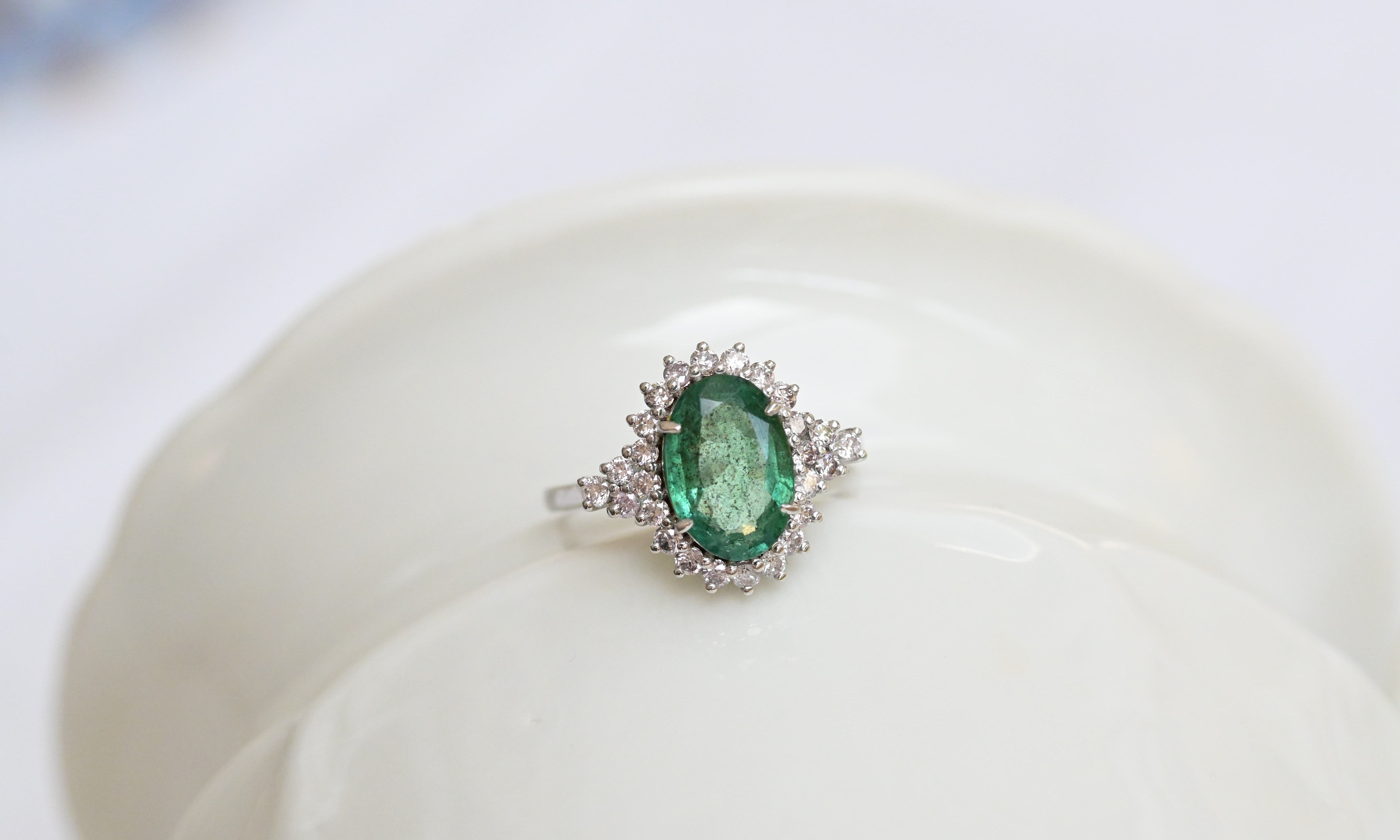 Vintage white gold ring with bluish green emerald and diamond accents.