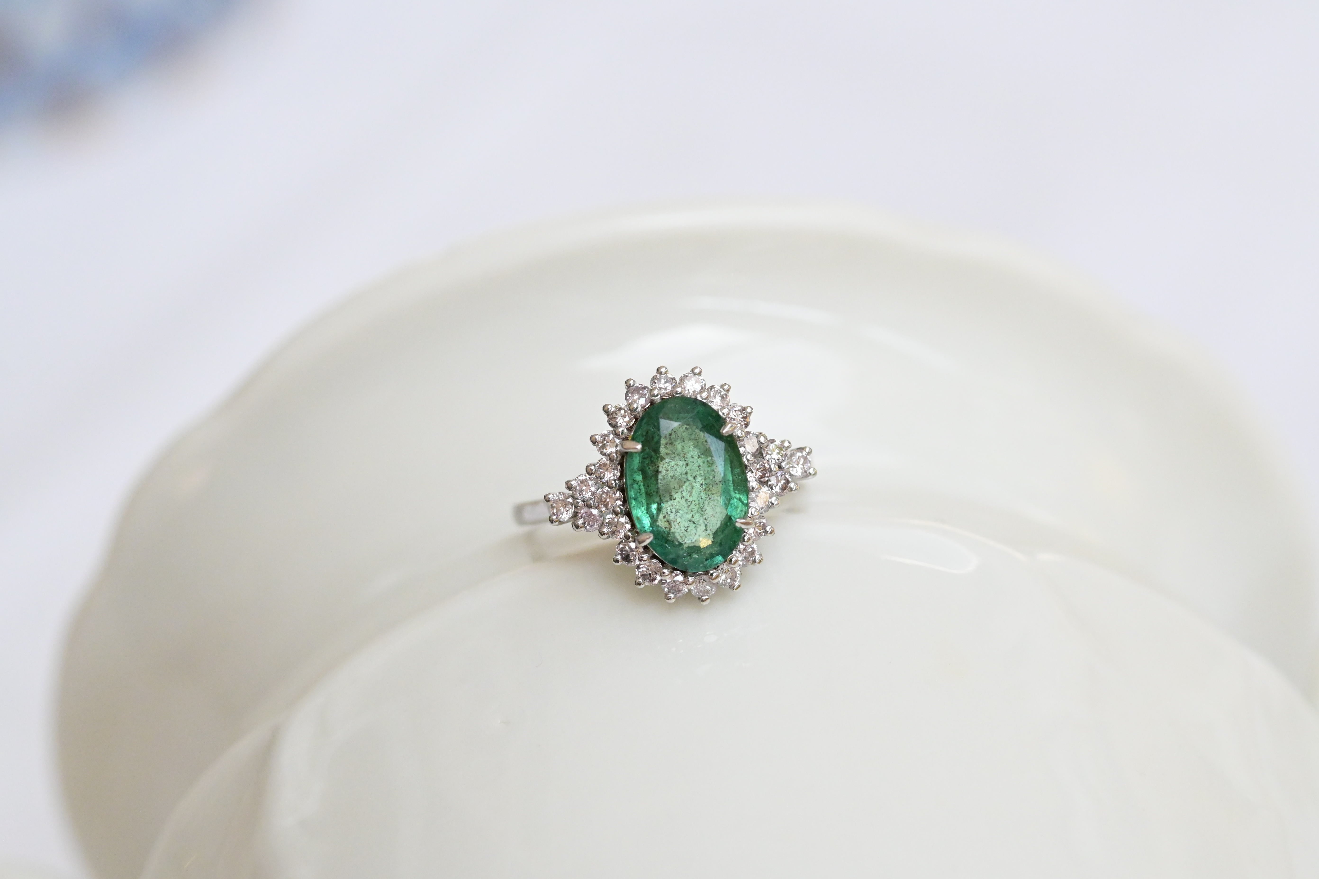 Vintage white gold ring with bluish green emerald and diamond accents.