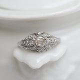 Elegant vintage cocktail ring featuring a central antique cut diamond and 16 eight-cut diamonds, set in white gold.